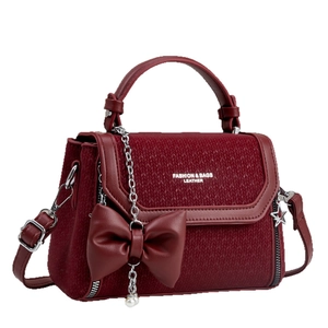 Elegant wine red crossbody handbag with bow ornament and pearl chain detail on white background