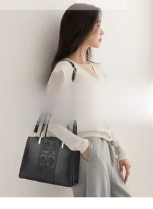 Detail of elegant black tote bag with rose embossed pattern shown on a female model