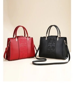 Detail of red and black handbags featuring elegant rose embossing and gold metal hardware