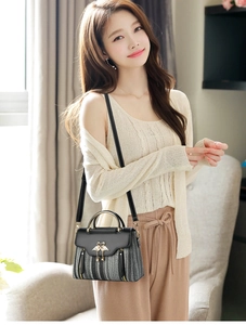 Detail of tweed crossbody bag featuring golden swan buckle and elegant tassel charm