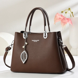 Sac à main marron en cuir avec bandoulière et pendentif feuille en métal et perle