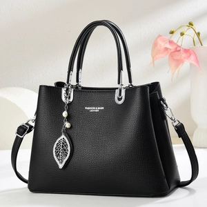 Sac à main chic en cuir noir avec ferrures argentées et pendentif perle et feuille