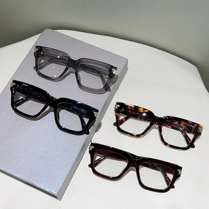 Close-up of four stylish square frame glasses in various colors with gold metal accents