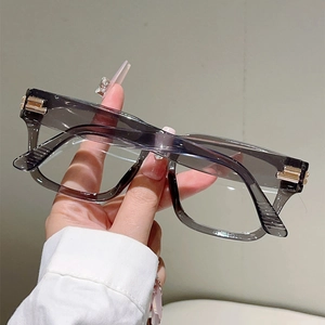 Detail of light grey square glasses frame with golden metal hinges and hand-held view