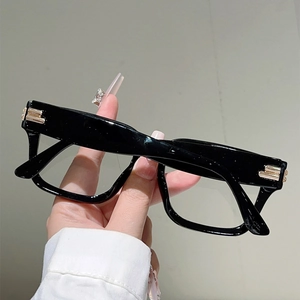 Detail of black rectangular frames featuring stacked gold metal accents on the temple