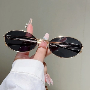 Détails de lunettes de soleil ovales avec monture en métal doré et branches profilées