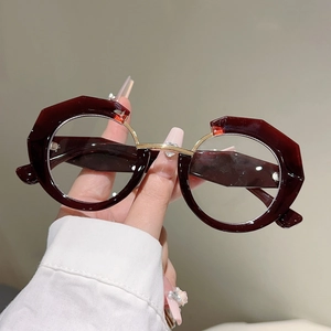 Detail of irregular burgundy frames with metallic gold bridge and geometric cut-out design