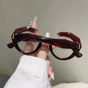 Close-up of geometric red-brown tortoiseshell glasses with gold metal and crystal details