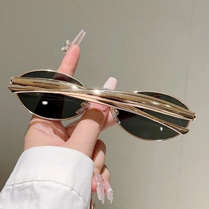 Détail de lunettes de soleil ovales avec branches en métal doré et verres foncés