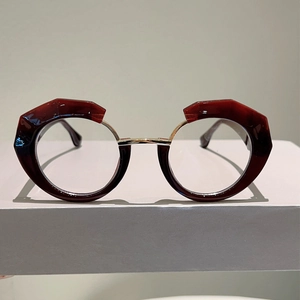 Detailed view of asymmetric deep red polygon and gold metal round frame glasses