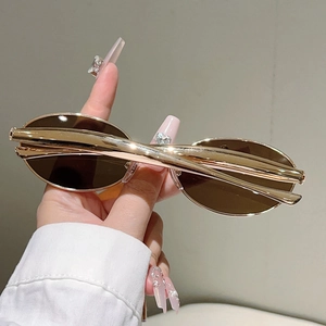 Détail de lunettes de soleil ovales avec branches dorées profilées et verres marron