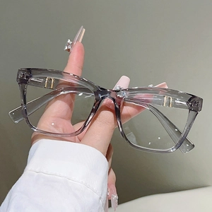 Detail der transparenten grauen Brille mit goldenen Metallakzenten am Scharnierbügel