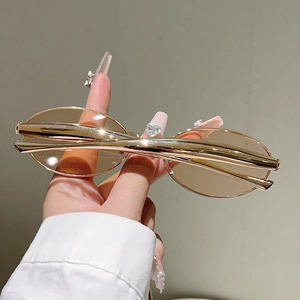 Détail de lunettes de soleil ovales avec branches métalliques dorées au design dauphin