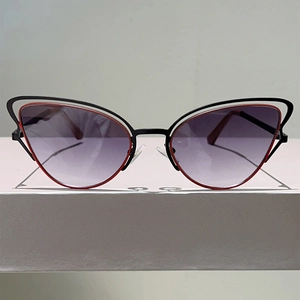 Détail des lunettes œil-de-chat avec monture en métal noir évidé et couches internes rouges