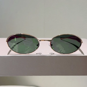 Détail de lunettes de soleil ovales vintage dorées avec verres vert foncé et branches