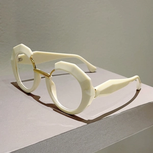 Detail of irregular cream resin frame with faceted texture and golden metal nose bridge