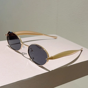 Lunettes de soleil rétro ovales avec monture en métal doré et verres noirs sur socle