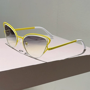 Détail de lunettes de soleil œil-de-chat avec monture bicolore jaune et blanc et verres