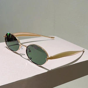 Détail des branches dorées profilées en forme de dauphin sur lunettes ovales