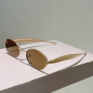 Détail de lunettes de soleil ovales avec monture métallique dorée et verres bruns