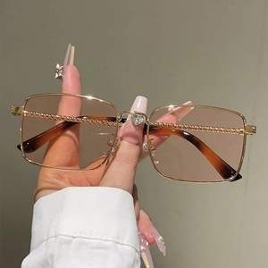 Detailed close-up of gold square sunglasses with twisted metal temples and heart detail