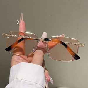 Detail of gold metal frame sunglasses with rope-textured engraving and orange lenses