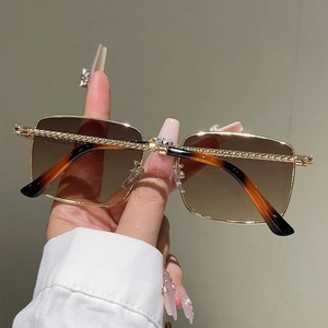 Detail of gold metal square frame sunglasses with twisted rope texture and orange lenses