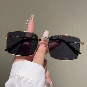 Close-up of gold metal square frame sunglasses with heart-shaped diamond and twisted temple