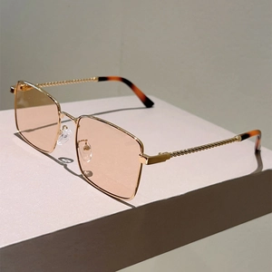 Detail of gold metal twisted temple design and orange square lenses on sun glasses