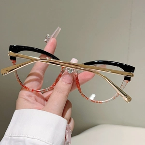 Detailaufnahme der Cat-Eye-Brille mit Schwarz-Gold-Kontrast und Metallbügeln