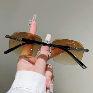 Close-up of star-patterned metal relief on rimless sunglasses with brown gradient lenses