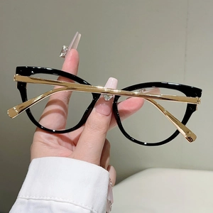 Details von schwarzer Oversize-Brille mit eleganten goldenen Metallbügeln in der Hand