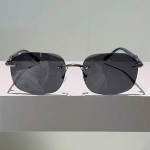 Detail of rimless punk sunglasses featuring dark grey lenses and silver metal components