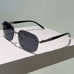Close-up of frameless sunglasses with grey gradient lenses and textured metal temples