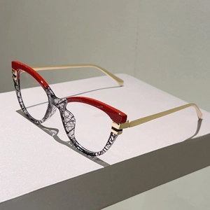 Detail der Cat-Eye-Brille mit rot strukturierter Oberseite und goldenen Bügeln