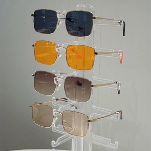 Square gold metal sunglasses with orange and gradient lenses on a display stand