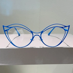 Detail of blue cat-eye metal frame with hollow double-line design on a display box