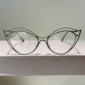 Detail of olive green cat-eye metal glasses frame with artistic hollow-out design