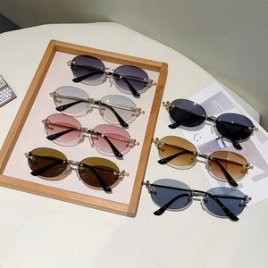 Vue à plat de lunettes de soleil ovales sans monture aux verres dégradés et branches dorées