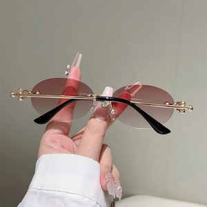 Détail de lunettes de soleil ovales sans monture avec perles dorées et strass discrets
