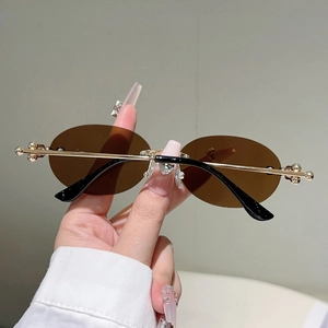Détail de lunettes de soleil ovales avec verres thé, monture or et pont en strass