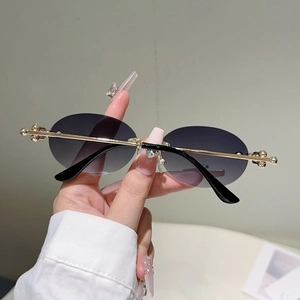 Détail de lunettes de soleil ovales en métal doré avec verres dégradés violets et sphères