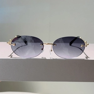 Détail de lunettes de soleil ovales sans monture avec charnières à billes dorées