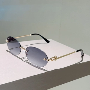 Détail des branches en métal doré avec design à maillons sphériques sur lunettes ovales
