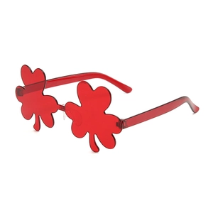 Detail of red shamrock-shaped party sunglasses made of transparent plastic material