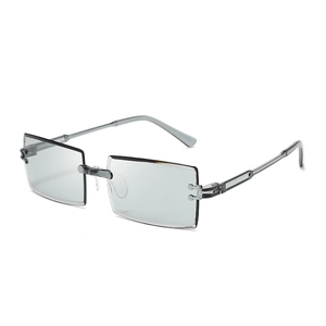 Close-up of frameless rectangular sunglasses with light gray lenses and metal hinge detail