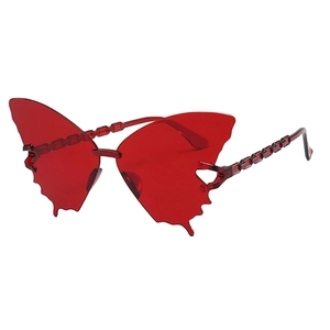 Détail de lunettes papillon rouges transparentes avec branches en chaîne et bords dentelés