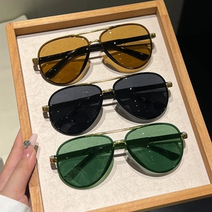 Close-up of pilot sunglasses with gold metal frames and tinted lenses on wooden display