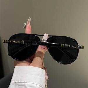 Detail view of black aviator sunglasses with gold PKR-ASBML branding on the temple arm