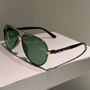 Classic aviator sunglasses with green lenses and gold metal bridge on grey platform